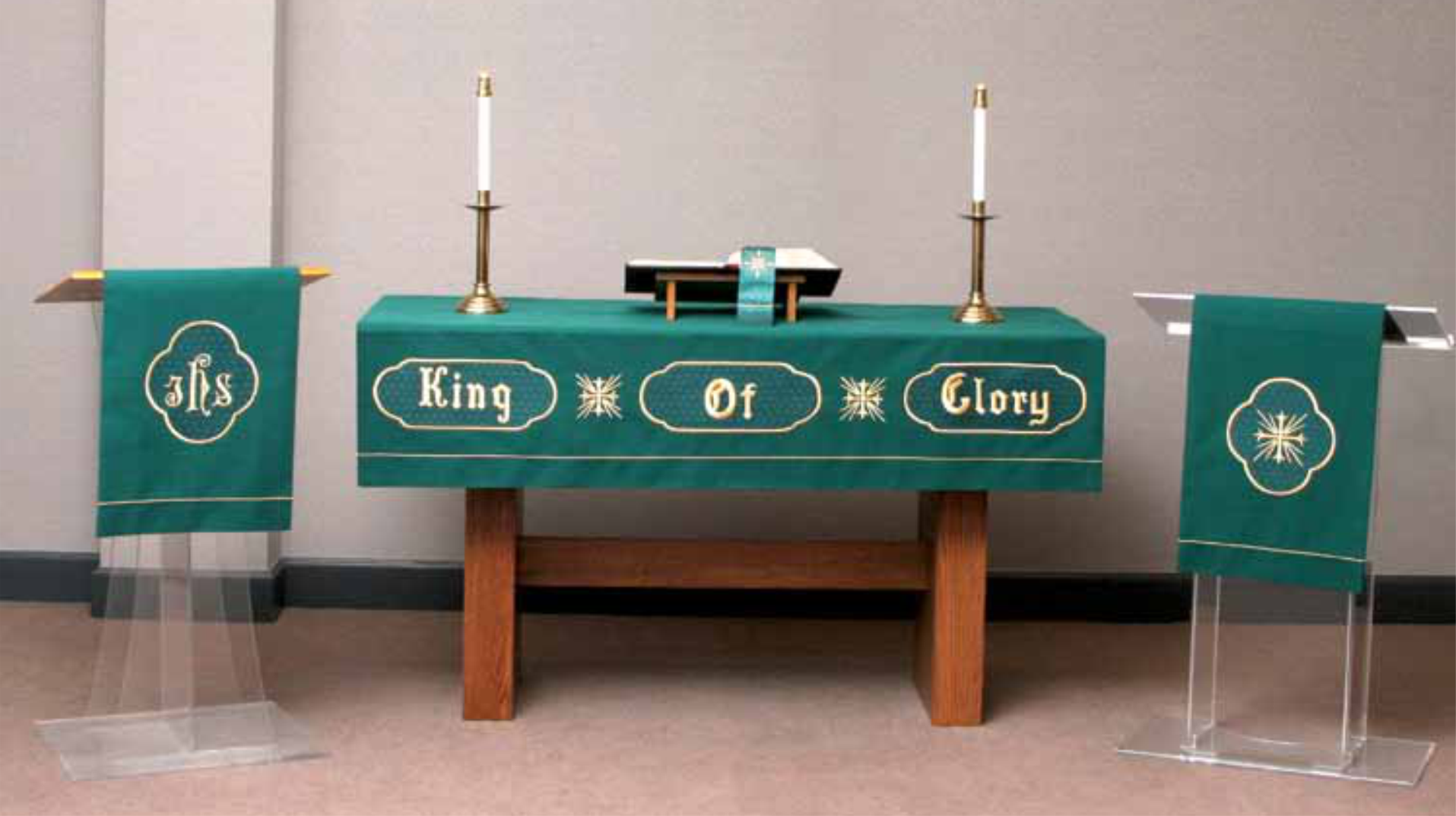 Eucharistic altar with green tablecloth, candles, and religious text in a church setting.