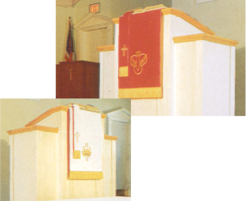 Pulpit with red and gold fabric draped over it, featuring religious symbols.