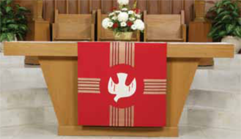 Red cloth with a white dove design draped over a wooden table in a church setting.
