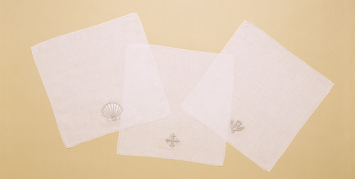 Three white napkins with embroidered designs on a beige background